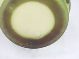 a green vase with a brown rim sitting on a white surface