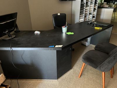 Bureau d'accueil composé d'un plan de travail noir, en angle…