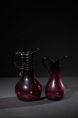 pair of red glass vases sitting on a table in a dark room
