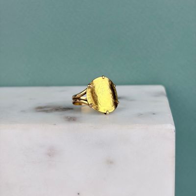 un gros plan d'une bague plaquée or posée sur un bloc de marbre