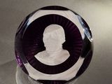 un presse-papier en verre violet sur lequel est représenté un homme