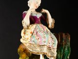 a figurine of a woman sitting on top of a tree stump