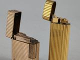 two gold colored lighters sitting next to each other on a gray surface