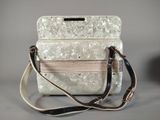a white purse with a brown strap on a table