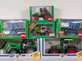 four green toy tractors in boxes on a white surface