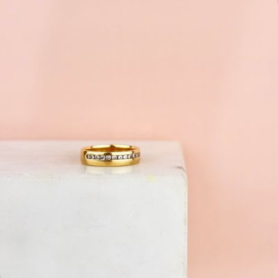 un gros plan d'une bague en or sertie de diamants posée sur un bloc blanc
