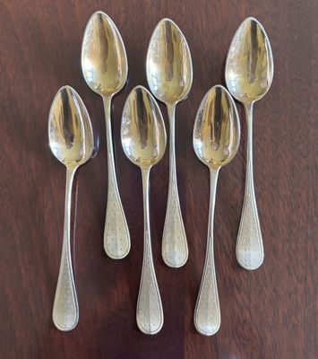 Six cuillères sont alignées sur une table en bois.