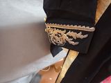 a close up of a black jacket with a gold broocher on it
