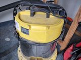 un aspirateur jaune posé par terre à côté d'un sac rouge