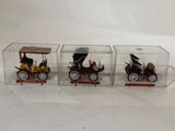 three toy cars in a clear box on a white surface