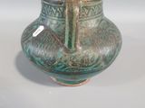 a green vase sitting on a table with a tag on it