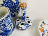 a blue and white vase, a candle holder, and a plate on a table