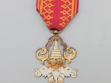 une image représentant une médaille rouge et dorée ornée d'une croix