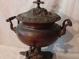 une urne antique en bronze avec un couvercle, posée sur un socle