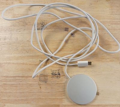 un câble blanc branché à un chargeur posé sur une table en bois