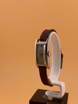 une montre posée sur un socle, sur une surface marron