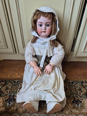 an antique doll sitting on a rug in a living room