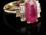 une bague ovale sertie d'un rubis et de diamants taillés en baguette sur un fond noir