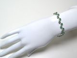 bracelet orné de pierres vertes sur la main d'un mannequin blanc