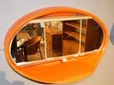 un miroir ovale de couleur orange accroché au mur d'une pièce