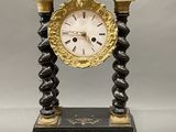 a black and gold clock on a stand with a key