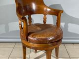 une photo d'une chaise en bois avec une assise en cuir, posée sur un sol carrelé