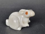 an image of a white rat with an orange eye sitting on a black surface