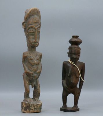 two wooden statues of a man and a woman with a vase on their head