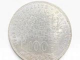 coin on a white surface with a white background and a tree in the center