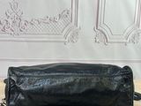 black leather handbag on a wooden table with a white wall in the background