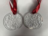 pair of clear glass ornaments with red ribbon on white background