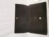 a black wallet with a button on it on a bed