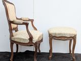 two chairs and a foot stool in a room with a wall in the background