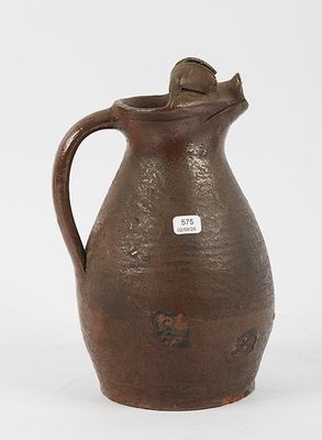 an old brown pitcher sitting on a white surface with a tag on it