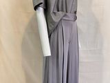 Le mannequin porte une robe grise avec une ceinture.