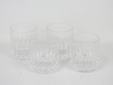 four clear glass tumblers sitting on a white surface