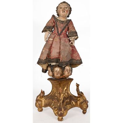 une statue ancienne en bois représentant une fillette avec une poupée, posée sur une table