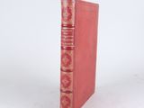 an old red book sitting on top of a white surface