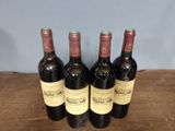 four bottles of wine are lined up on a wooden table