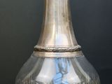 un vase en verre avec un couvercle en argent posé sur une table