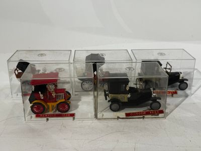 three toy cars in a clear box on a white surface