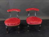 a pair of red velvet chairs with black legs