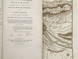 un livre ouvert, sur lequel figure une carte, posé sur une table