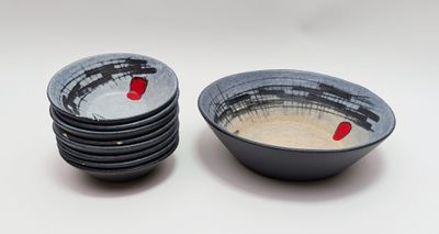 four black and white bowls with red designs on them on a white surface