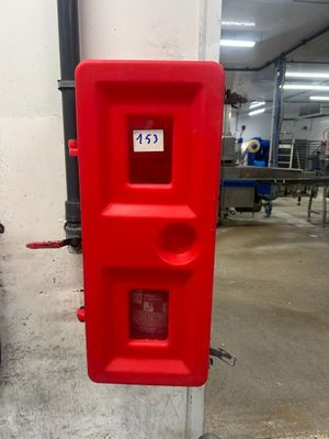 une borne d'incendie rouge située contre un mur