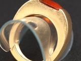 an image of a ring with a red stone in it on a black surface