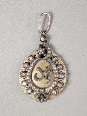 a close up of a silver and gold pendant on a white surface