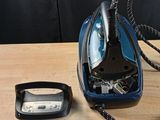 un fer à repasser à vapeur bleu et noir posé sur une table en bois