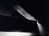 black and white photograph of a person using a large knife to cut a piece of paper
