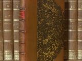 un livre posé sur une étagère, devant une pile de livres